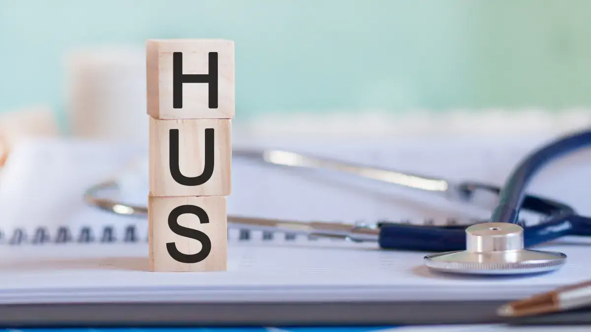 Holzwürfel mit Buchstaben "HUS", daneben ein Stethoskop