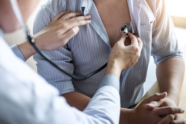 Arzt, der den Patienten mit einem Stethoskop überprüft und untersucht