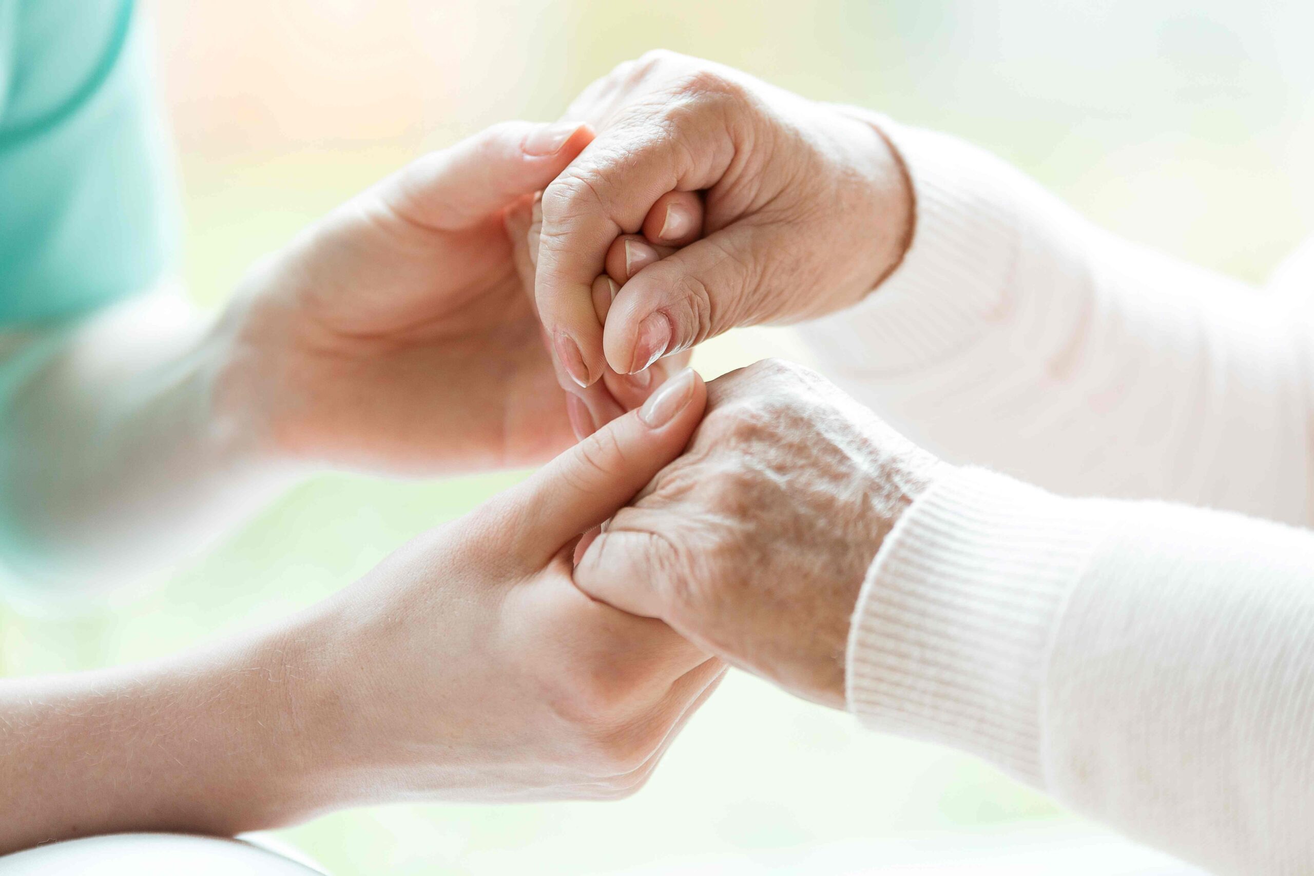 Krankenschwester hält alte Dame an den Händen