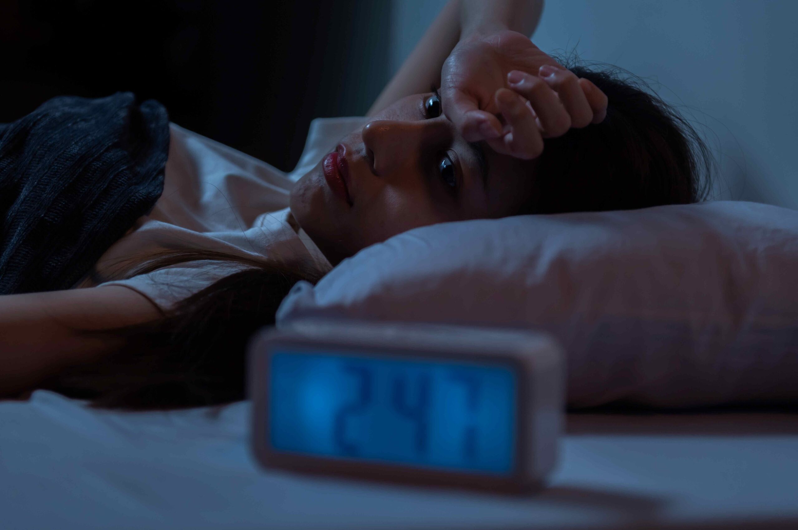 Frau liegt nachts im Bett und leidet unter Insomnie.