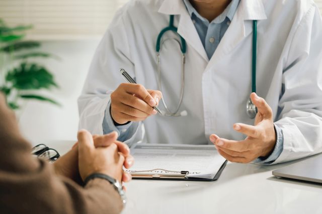 Ein professioneller Arzt in einer weißen medizinischen Uniform spricht mit einem Patienten