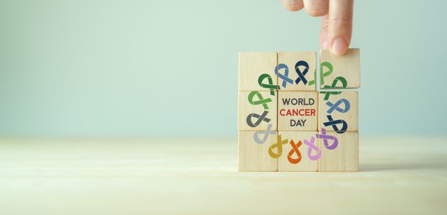 Weltkrebstag (4. Februar). Bunte Bänder auf hölzernen Würfelblöcken im Hintergrund, Krebsbewusstsein, nationaler Tag der Krebsüberlebenden. Gesundheits- und Medizinkonzept.