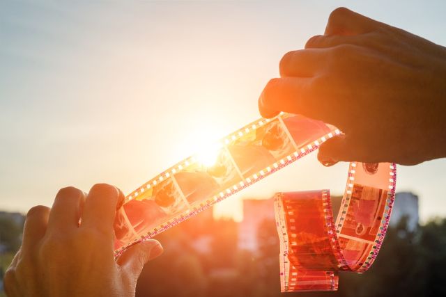 Zu sehen sind Hände, die einen Fotofilm halten, als Symbolbild für Erinnerung und Vergessen.