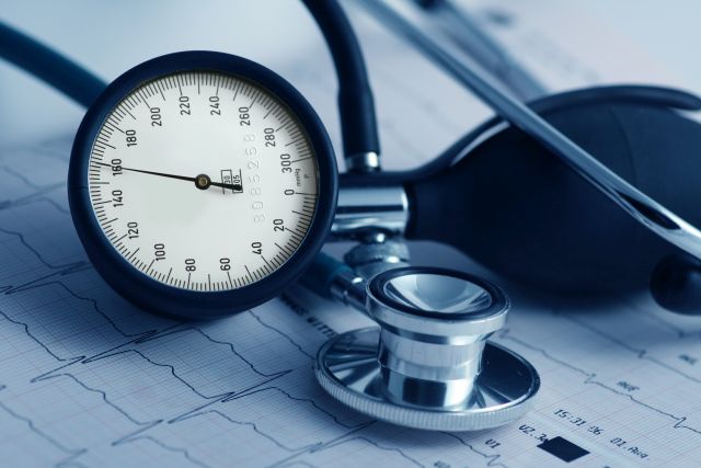 Blutdruckmessgerät und Stethoskop auf einem EKG-Diagramm