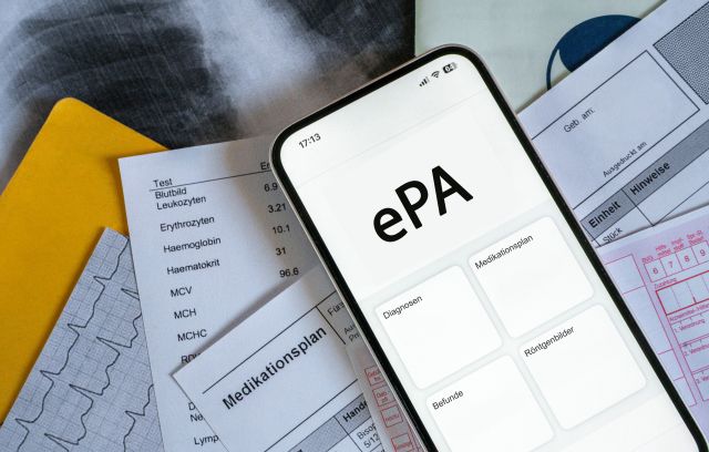 Smartphone mit ePA-App, im Hintergrund medizinische Dokumente