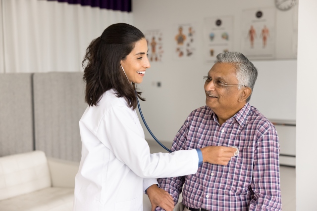 Ärztin führt eine kardiologische Untersuchung bei einem Patienten durch, symbolisiert kardiovaskuläre Prävention.