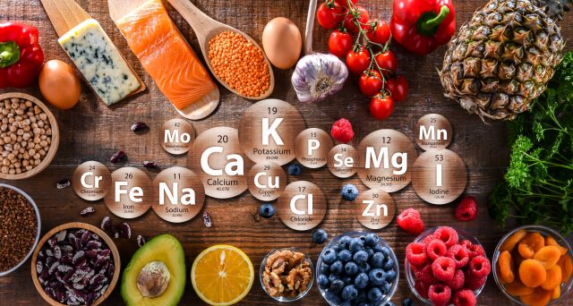 Lebensmittel mit hohem Nährstoffgehalt, darunter Lachs, Käse, Obst, Gemüse, Hülsenfrüchte und Nüsse, kombiniert mit chemischen Symbolen für Mineralstoffe wie Kalium, Calcium, Magnesium und Eisen.