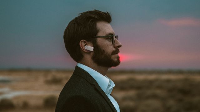 Seitenansicht eines Mannes mit drahtlosem Ohrhörer, der innovative Sensoren für Gesundheitsmessungen integriert.