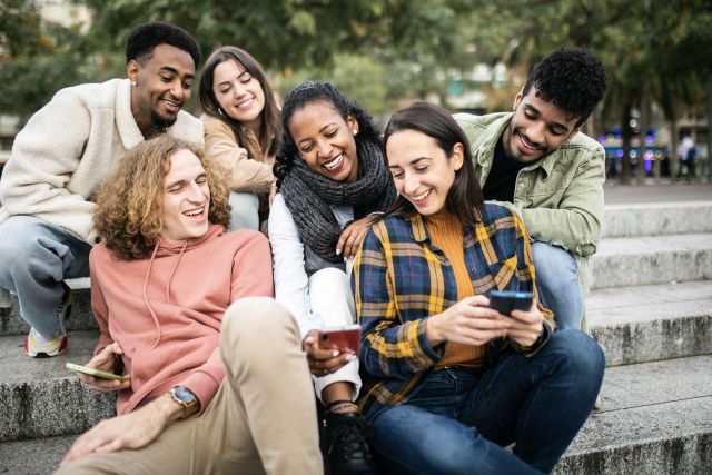 Multikulturelle Gruppe junger trendiger Freunde, die Mobiltelefone und soziale Medien nutzen