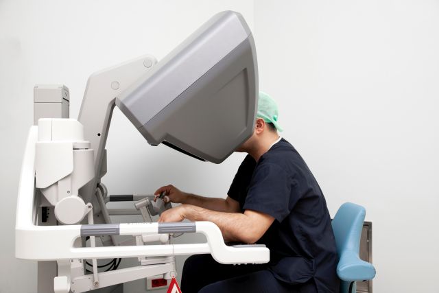 Chirurg arbeitet am Da Vinci Operationsroboter in einem modernen Operationssaal.