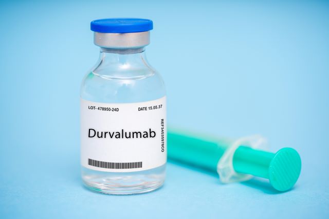 Eine Ampulle mit dem Medikament Durvalumab und einer Spritze auf blauem Hintergrund.