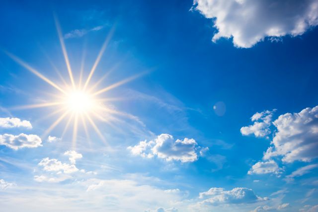 Blauer Himmel mit Sonne und Wolken