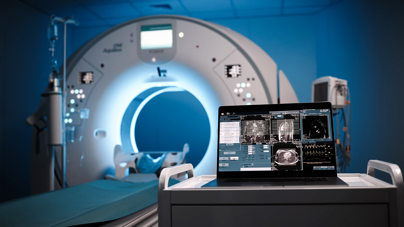 CT-Scanner in einem medizinischen Raum mit Laptop, der Bildgebungsdaten anzeigt