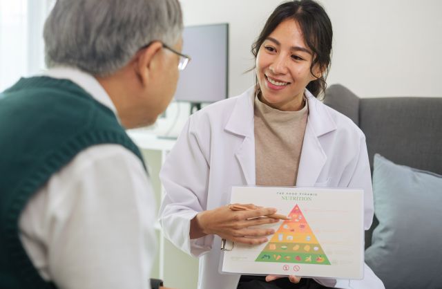 Eine Ernährungsberaterin erklärt einem Patienten die Ernährungspyramide im Rahmen einer Ernährungsberatung bei Krebs.