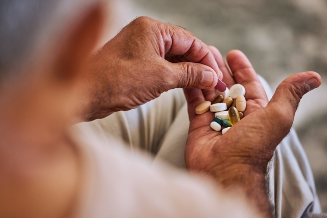 Ältere Person hält verschiedene Tabletten in der Hand, symbolisch für die Behandlung mit SGLT2-Inhibitoren.