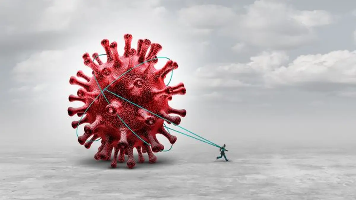 Ein Mensch zieht ein riesiges rotes Virus, das die Herausforderungen der Pandemie symbolisiert.