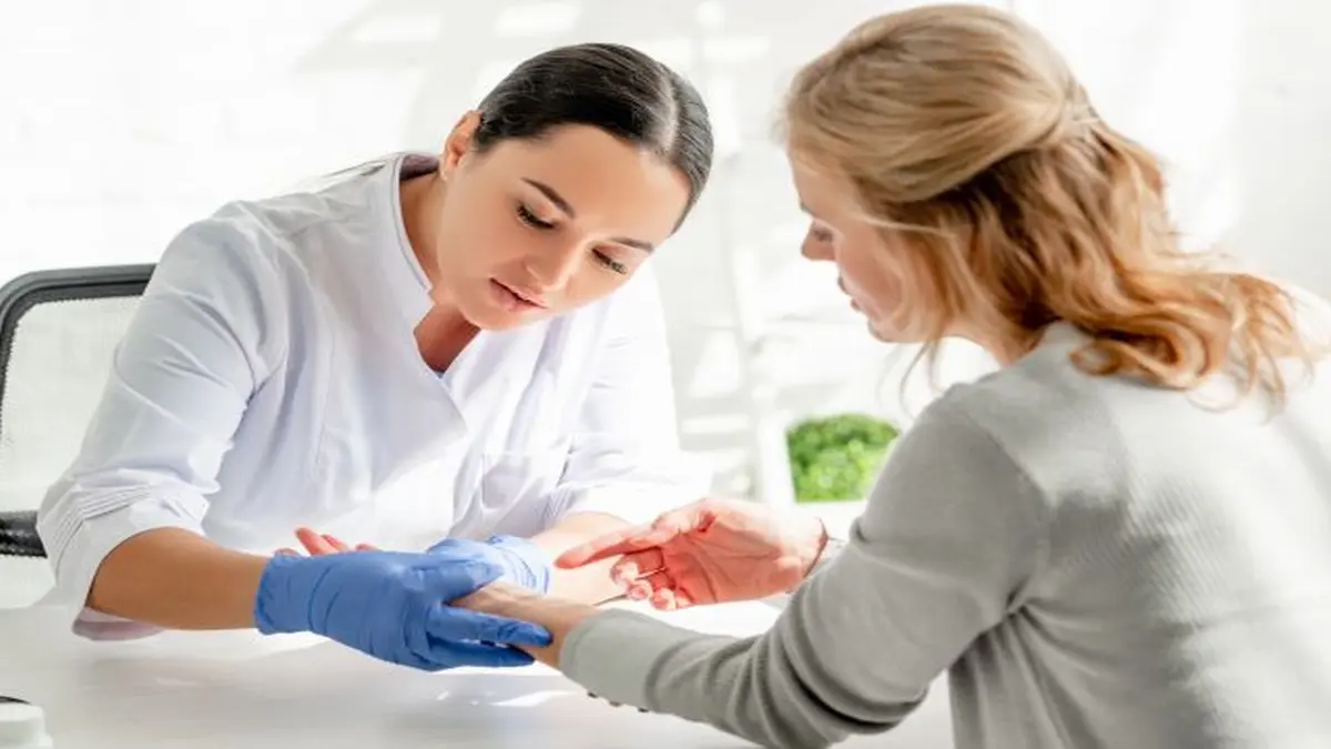 Arzt untersucht die Hand eines Patienten während einer Beratung in einer hellen Praxis.