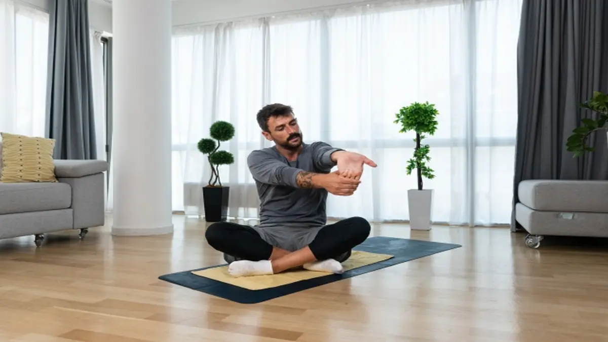 Person führt Dehnübungen in einem Wohnraum aus, symbolisiert die positiven Auswirkungen von individuellem Heimtraining bei Kopf-Hals-Tumoren.