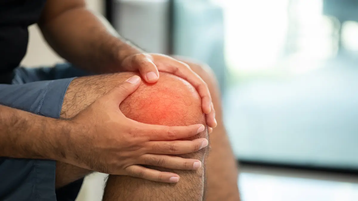 Mann hält sich ein schmerzendes, gerötetes Knie.
