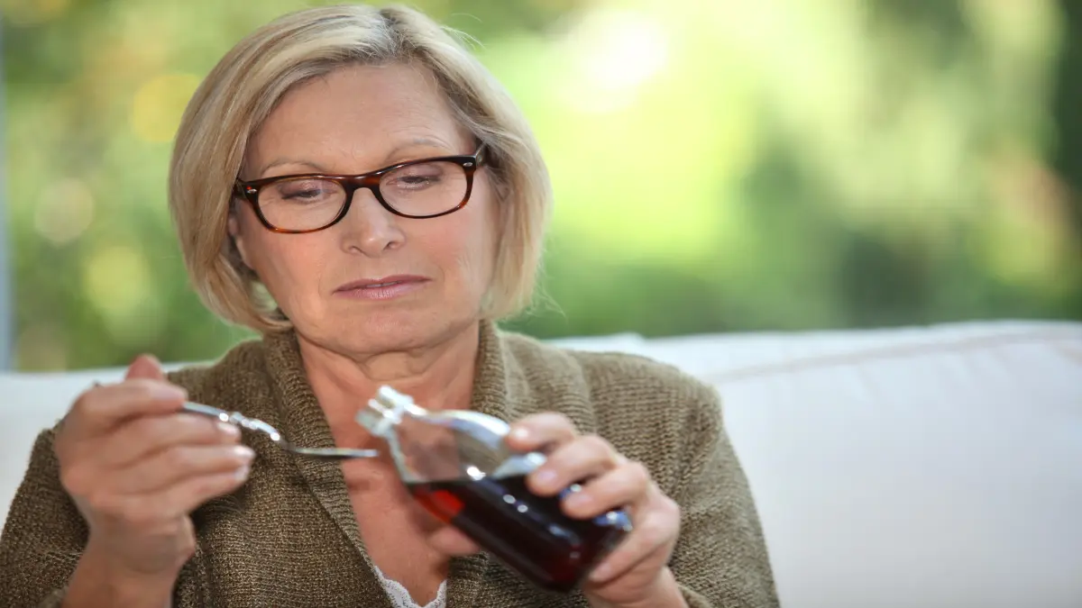 Frau, die sich Hustensaft auf einen Löffel schüttet