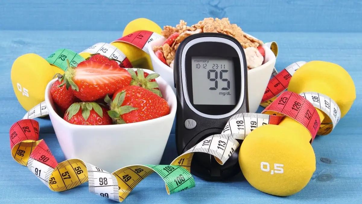 Eine Schale mit frischen Erdbeeren, eine Schale mit Müsli, ein Blutzuckermessgerät und gelbe Hanteln, umgeben von Maßbändern, symbolisieren gesunde Ernährung und Bewegung bei Diabetes. © ratmaner – stock.adobe.com