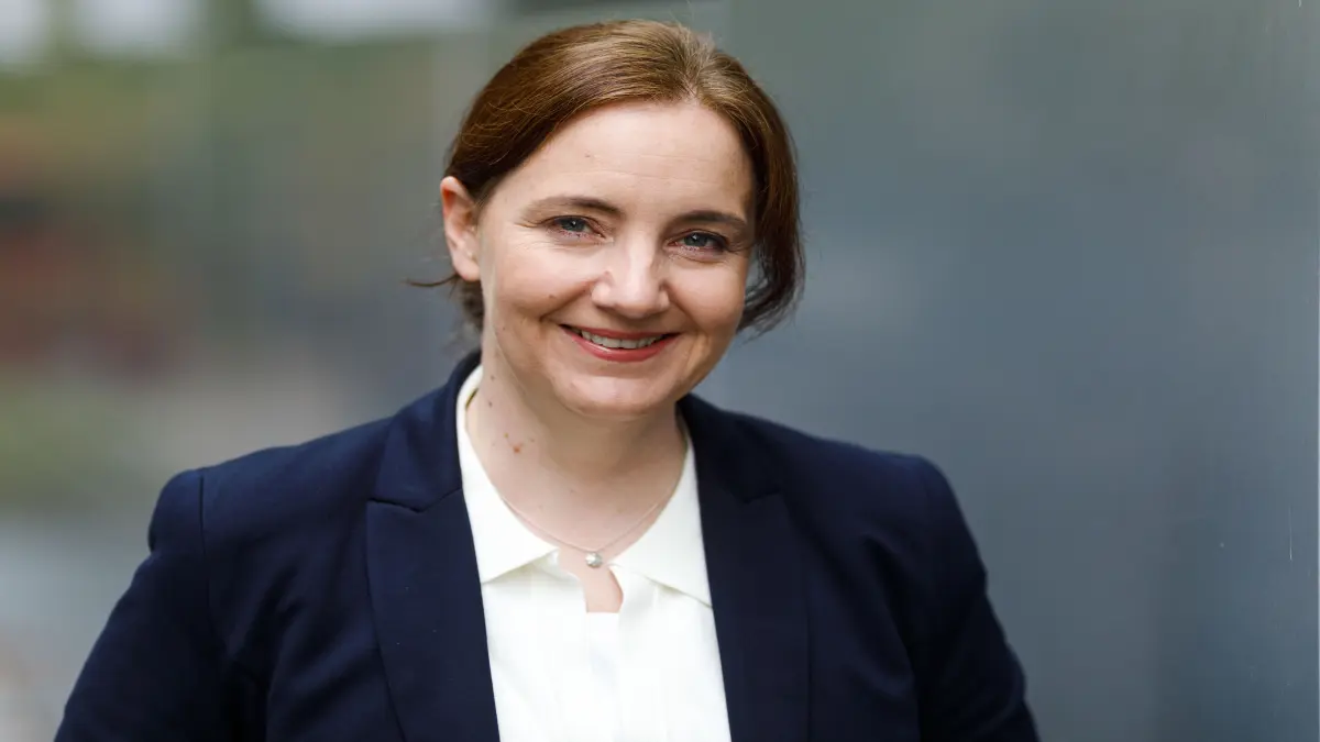 Person im Business-Outfit vor unscharfem Hintergrund, aufgenommen am ISAS.