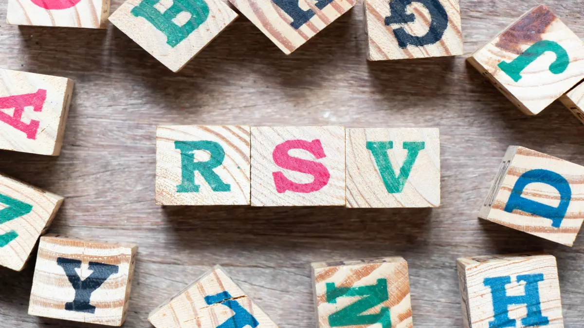 Holzwürfel mit Buchstaben RSV auf einer Holzoberfläche, umgeben von weiteren Buchstabenwürfeln.