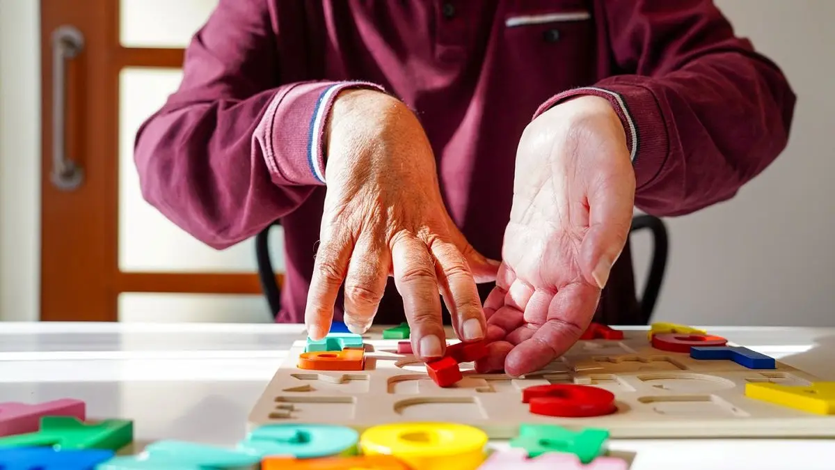 Hands performing rehabilitation exercises with colorful puzzle pieces, focusing on motor skills and therapy for ALS.