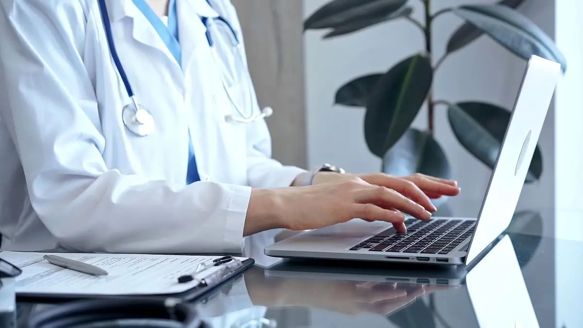 Arzt im weißen Kittel arbeitet am Laptop – digitale Medizin und Dokumentation