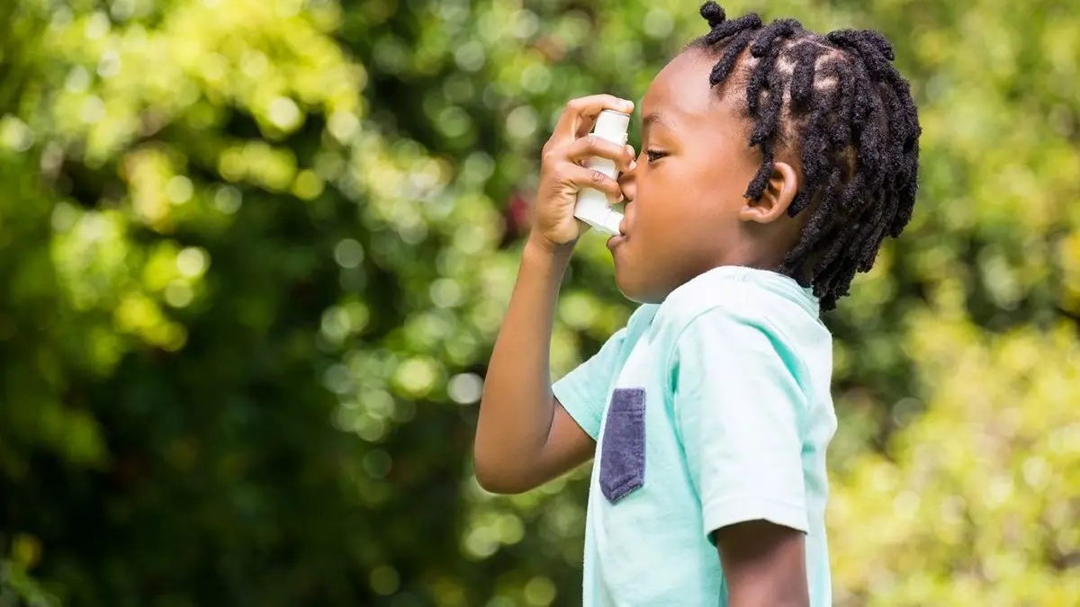 Ein Kind verwendet einen Inhalator zur Behandlung von Asthma in einer grünen, natürlichen Umgebung.