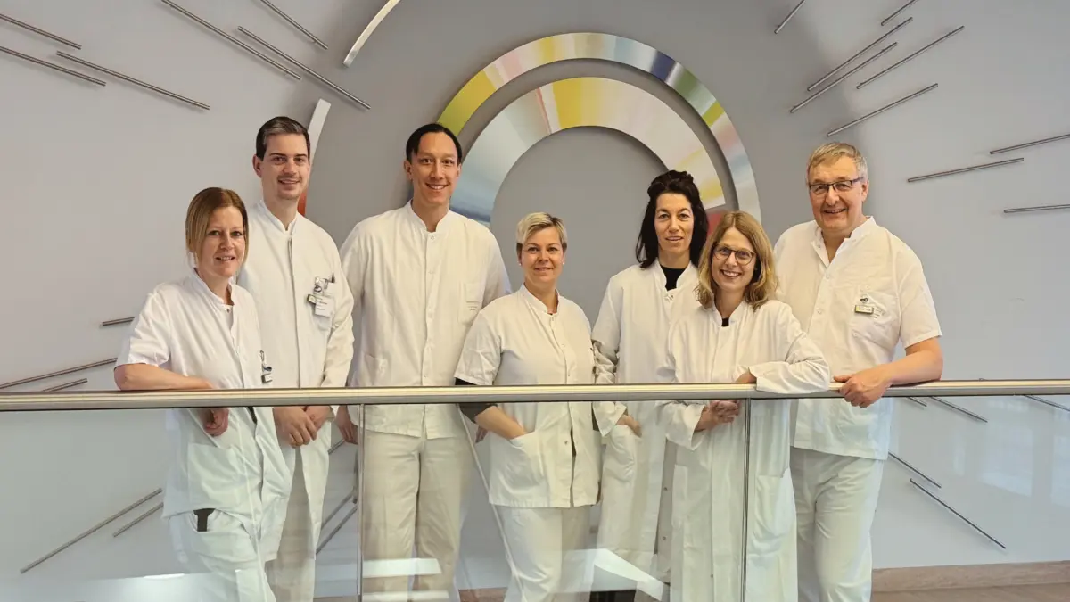 Bench-to-Bedside Team aus Endokrinologie und Nuklearmedizin des UKW in weißer Arbeitskleidung vor Wanddeko