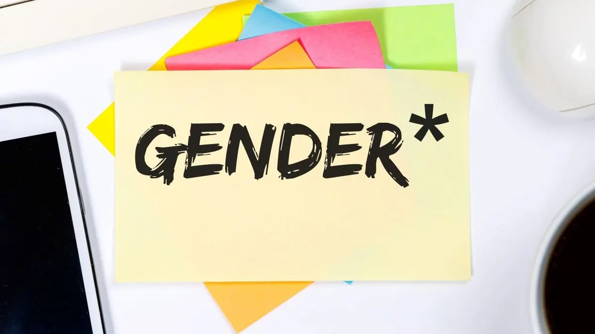 Post-it mit der Aufschrift „Gender*“ auf einem Schreibtisch, umgeben von bunten Notizzetteln und Büroartikeln.