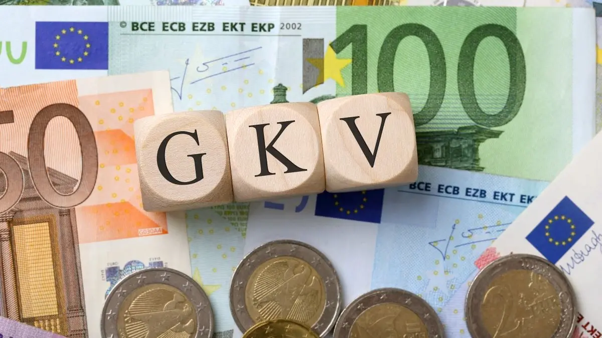 Holzwürfel mit der Aufschrift GKV auf Euro-Münzen und Banknoten, Symbol für gesetzliche Krankenversicherung