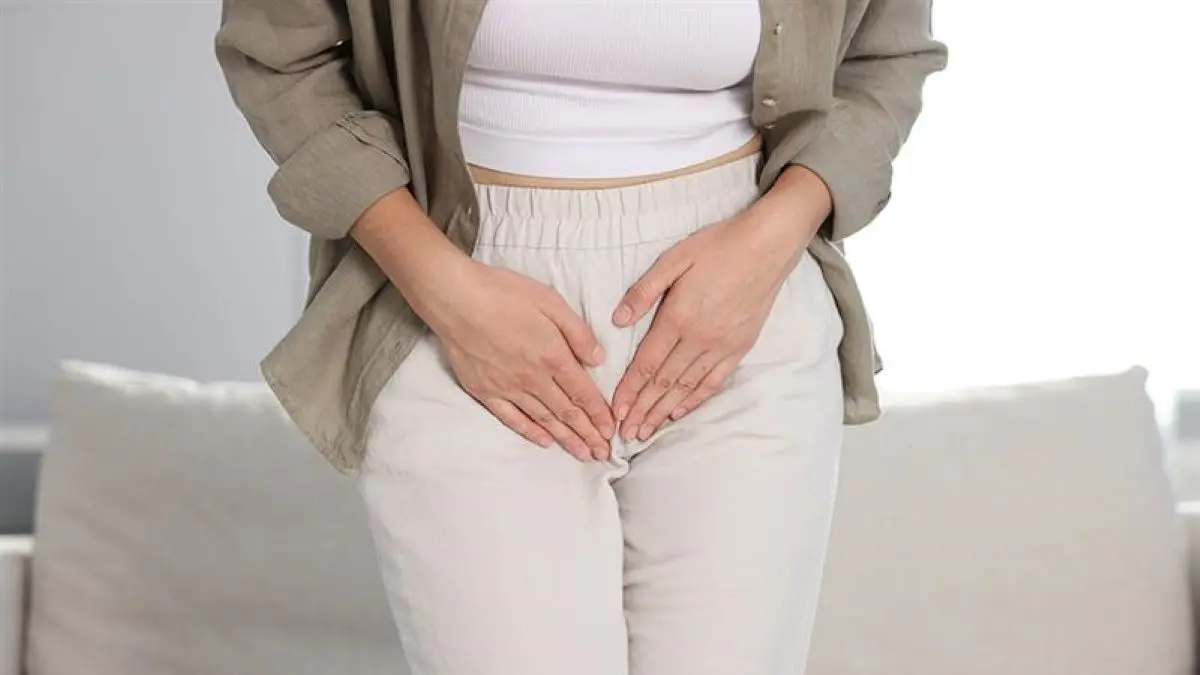Frau hält ihre Hände vor den Unterbauch, symbolisch für Harninkontinenz.