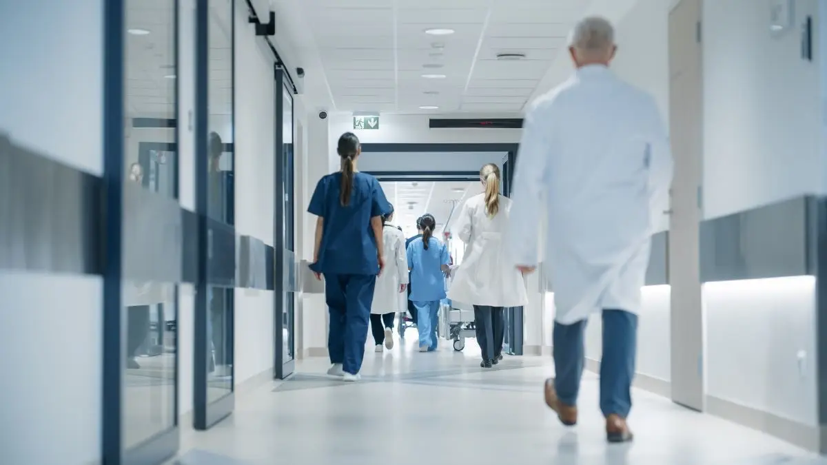 Medizinisches Personal in einem modernen Krankenhausflur, das sich auf dem Weg zu Patienten oder Untersuchungen befindet.