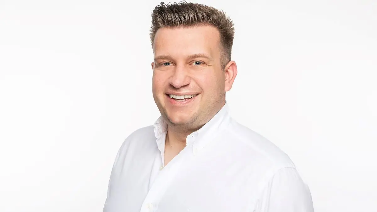 Portrait von Max Tischler in einem weißen Hemd vor neutralem Hintergrund.