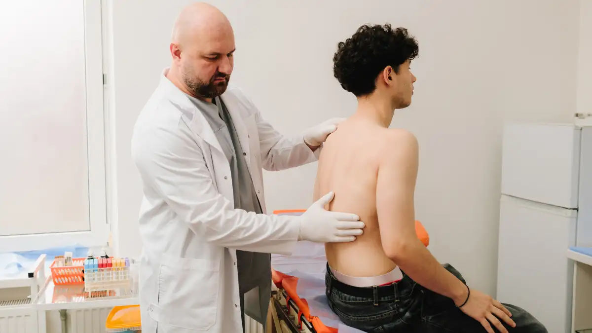 Ein Arzt klopft die Nieren eines Patienten mit freiem Oberkörper ab.
