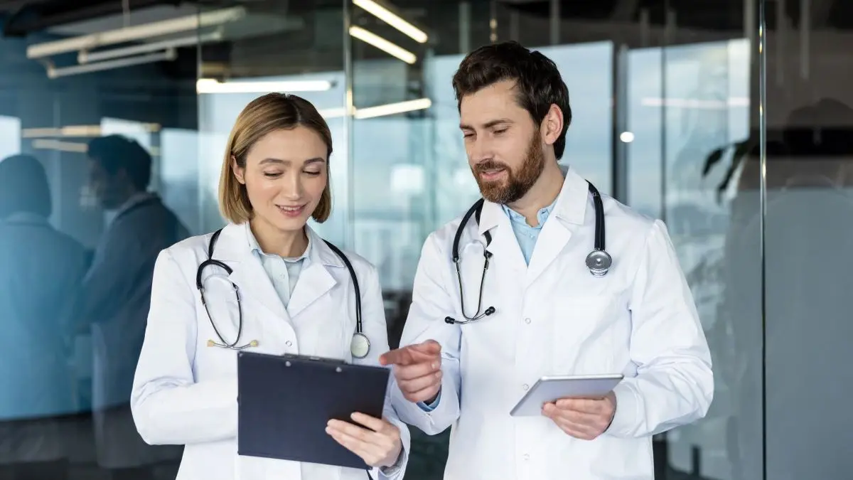 Ärzte-Team bei medizinischer Besprechung mit Tablet und Klemmbrett in moderner Klinik