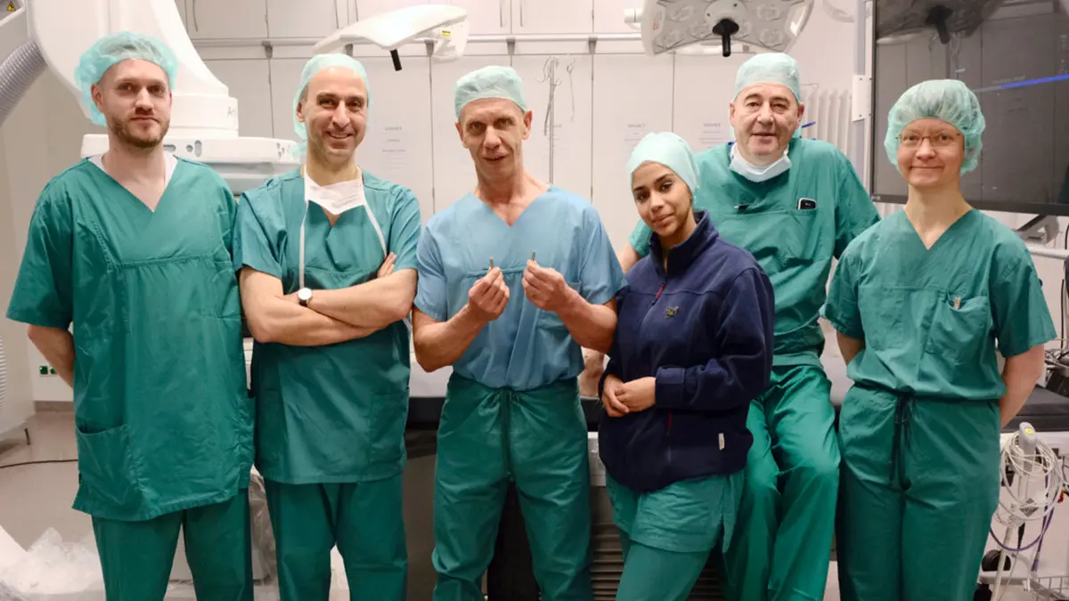 Das Kardiologie-Team des UKMA steht vor einer Operation im OP: Mitarbeiter von Abbott, Prof. Dr. Akin, Prof. Dr. Kuschyk, Kabakci, Götz und Dr. Sattler in OP-Kleidung
