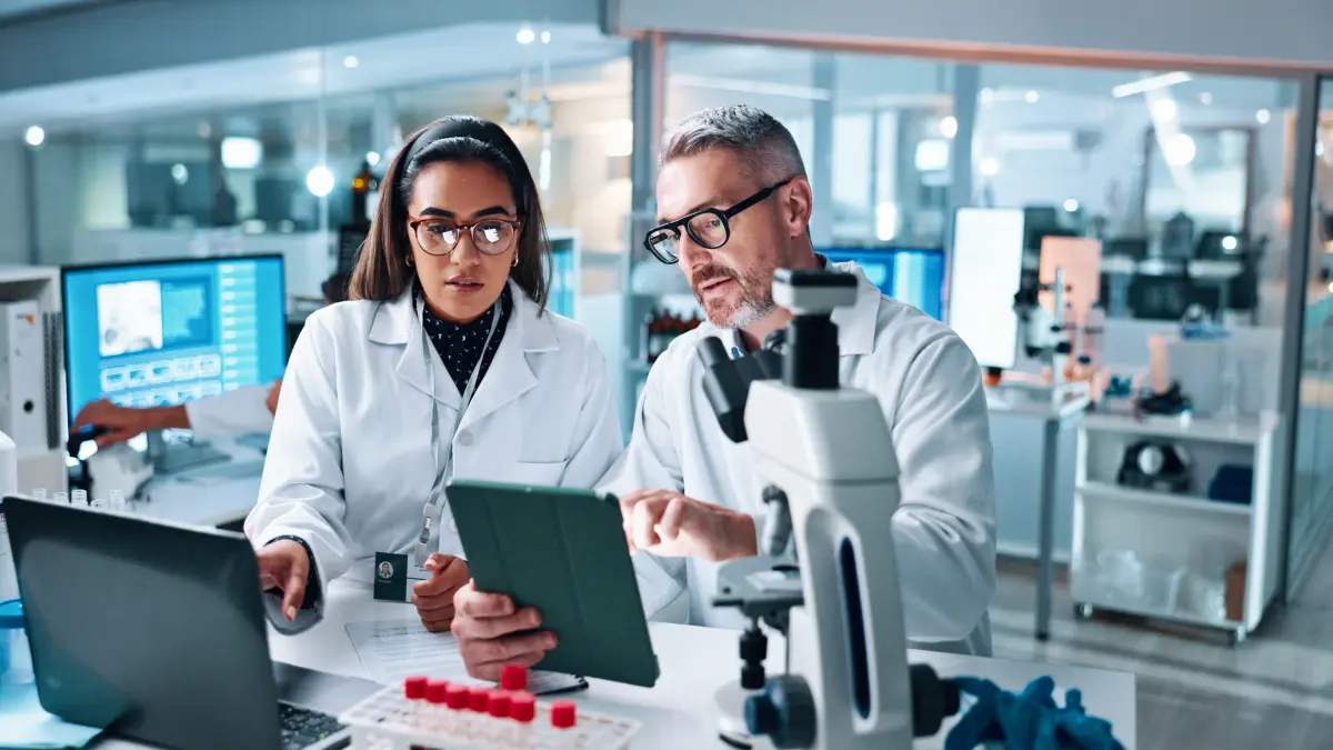 Zwei Wissenschaftler in weißen Kitteln besprechen Studiendaten im Labor