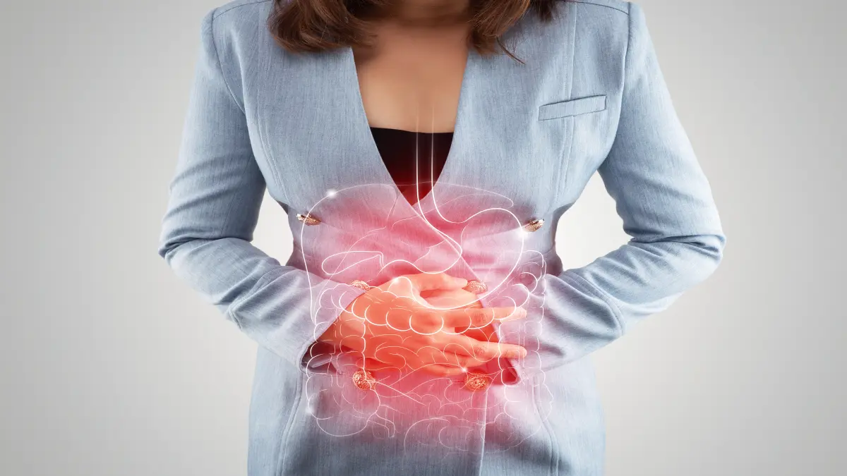 Frau hält sich den Bauch mit illustrierter Darstellung des Verdauungstrakts – Symbolbild für Morbus Crohn und Ernährung