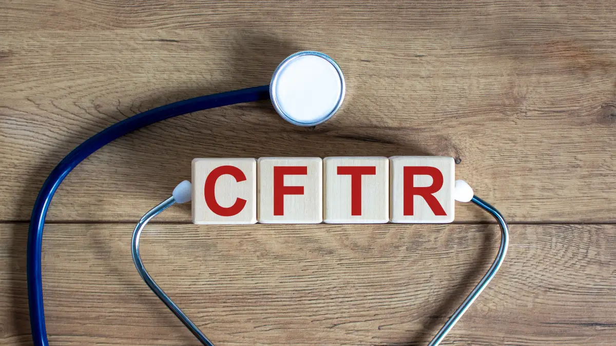 Holzwürfel mit der Aufschrift „CFTR“ und Stethoskop auf Holzhintergrund.