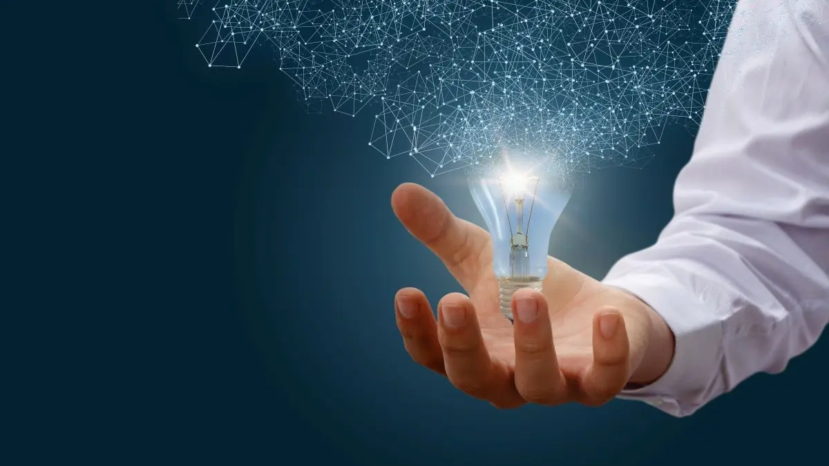 Hand haelt leuchtende Gluehbirne mit digitalem Netzwerk als Symbol fuer neue Perspektiven in der Basalzellkarzinom-Forschung