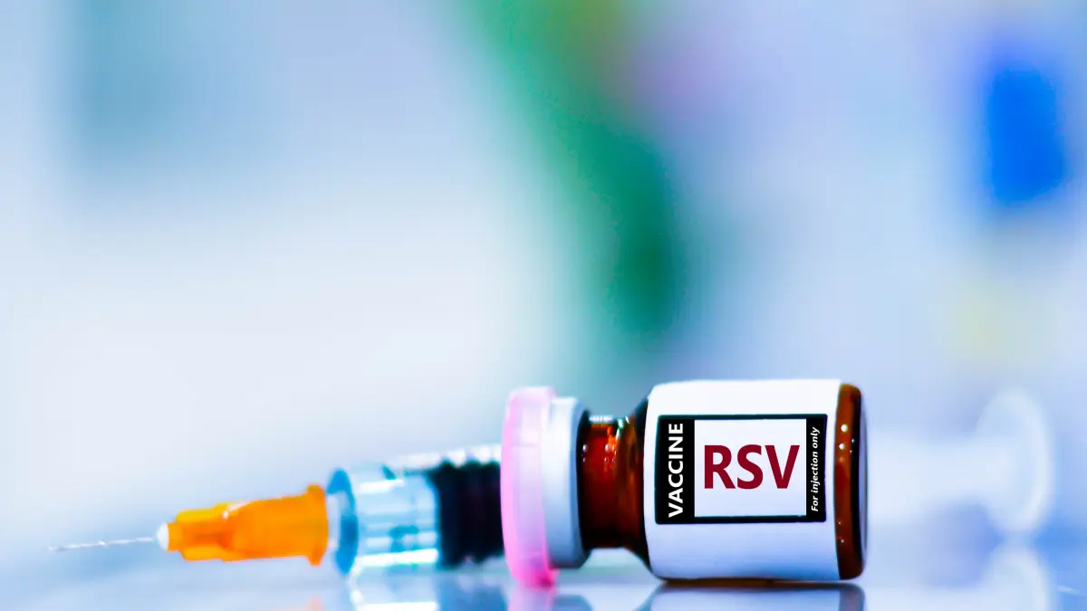 RSV-Impfung: Nahaufnahme einer Vakzine mit Aufschrift RSV und Spritze auf blauem Hintergrund