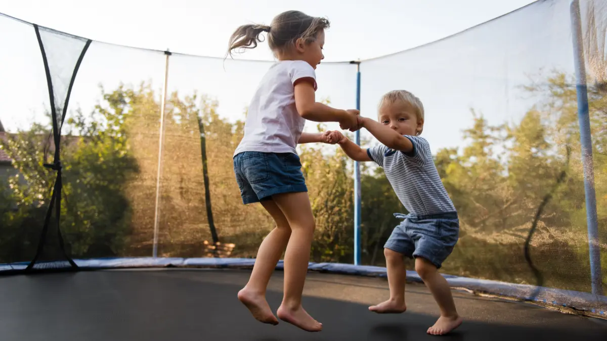 Zwei kleine Kinder springen zusammen auf einem Trampolin