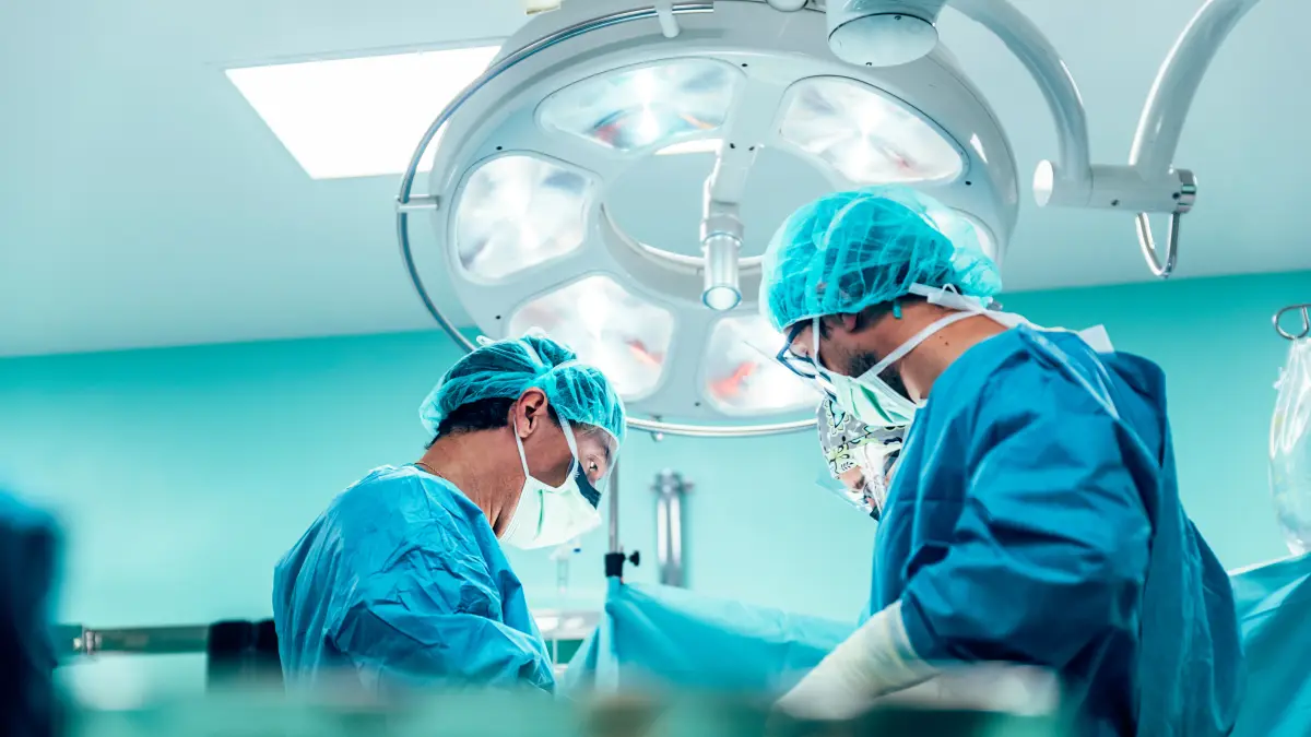 Zwei Chirurgen im Operationssaal bei einer Brustkrebsoperation unter dem OP-Scheinwerfer