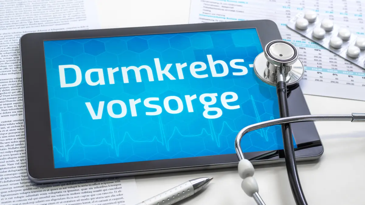 Tablet mit dem Schriftzug „Darmkrebsvorsorge", daneben ein Stethoskop und Tabletten