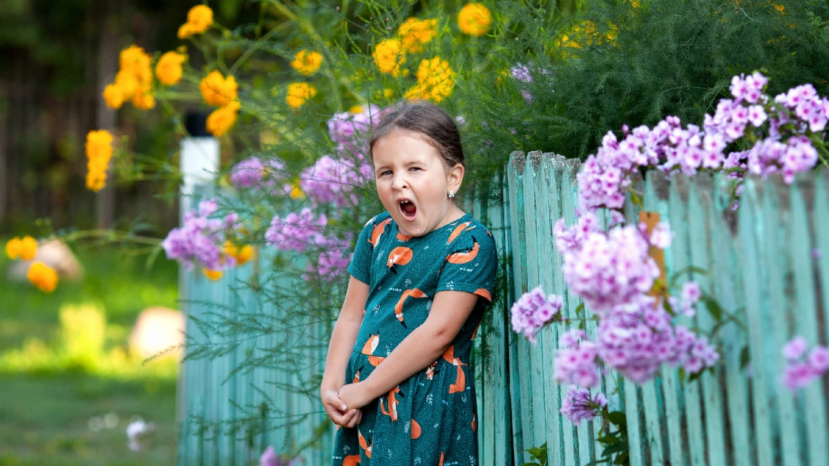 Gähnendes Mädchen im Frühlingsgarten – Symbolbild Frühjahrsmüdigkeit bei Kindern
