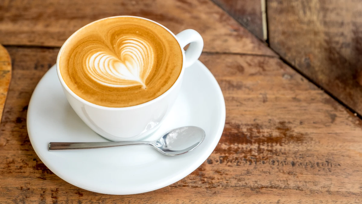 Tasse Cappuccino mit Latte-Art-Herz auf Holztisch – Kaffee und Demenzschutz