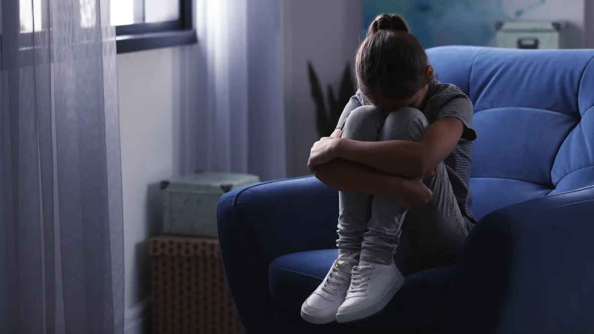 Depressives Mädchen sitzt zu Hause in einem Sessel